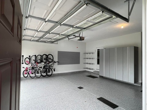 Slatwall storage system with hooks and shelving above a coated concrete garage floor