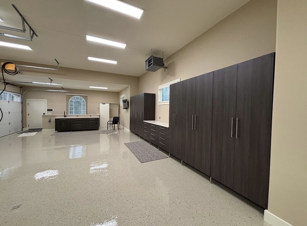 Organized two-car garage with wall cabinets, workbench area, and flake-coated concrete floor